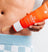 Close-up of a person applying Meridian's bright orange "The Scrub" exfoliating grooming product on their abdomen.