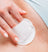 Close-up of a hand using a cotton pad to gently cleanse irritated skin.