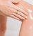 Close-up of a hand with a gold ring applying moisturizer to smooth, glowing skin on a knee.