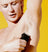 Man trimming underarm hair with electric trimmer against bright yellow background for personal grooming.