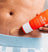 Exfoliating body scrub cream being applied on abdomen, skincare product for smooth, healthy skin, men's grooming routine.