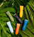 Six colorful water-resistant electric grooming trimmers arranged on large green tropical leaves with water droplets.