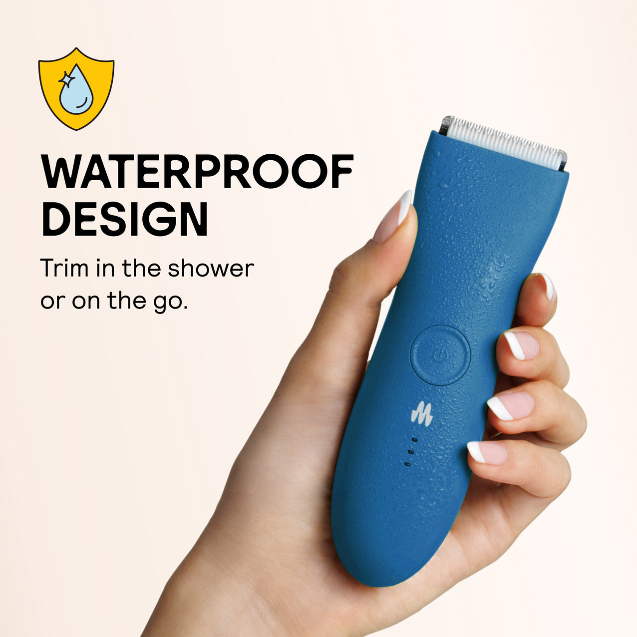 Waterproof blue electric hair trimmer with ergonomic design held in hand, covered in water droplets.
