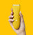 Yellow cordless electric hair trimmer held by hand with French manicure on vibrant yellow background.