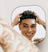 Smiling young man with curly hair and tattoos styling his hair while looking in the mirror.