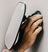 Hand with a tattoo adjusting a suction cup mirror mounted on a wall.