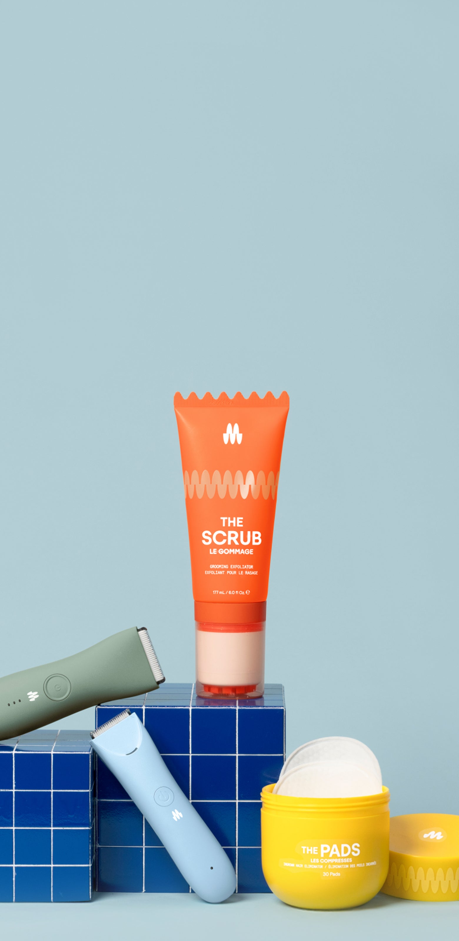 Skincare products including orange sunscreen tube, yellow moisturizer jar, blue lip balm, and gray roller on blue tiles with light blue background.