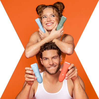 Smiling woman with hair buns holding pastel skincare devices above happy man in white tank top against orange background