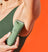 Cordless electric hair trimmer used for grooming armpit hair, woman in green tank top with orange background.