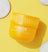 Yellow container of "The Pads" facial exfoliating pads with cotton pads on a bright yellow background.