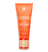 Orange exfoliating face scrub tube with gold and beige pump, labeled "The Scrub" for gentle skin renewal and detox.