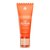 Orange exfoliating face scrub tube with gold and beige pump, labeled "The Scrub" for gentle skin renewal and detox.