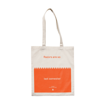 Beige tote bag with orange and white text that reads "Razors are so last semester" and a brand tagline at the bottom.