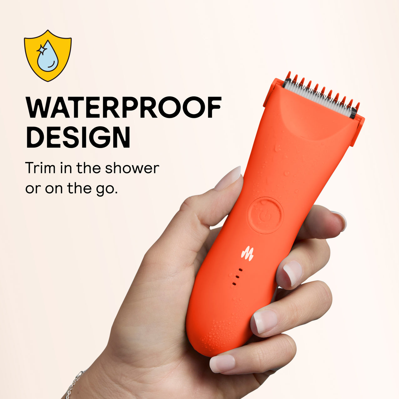 Compact orange waterproof electric trimmer with water droplets, held in hand for shower or travel use.