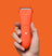 Orange cordless hair clipper with power button and LED indicators held by hand against orange background.
