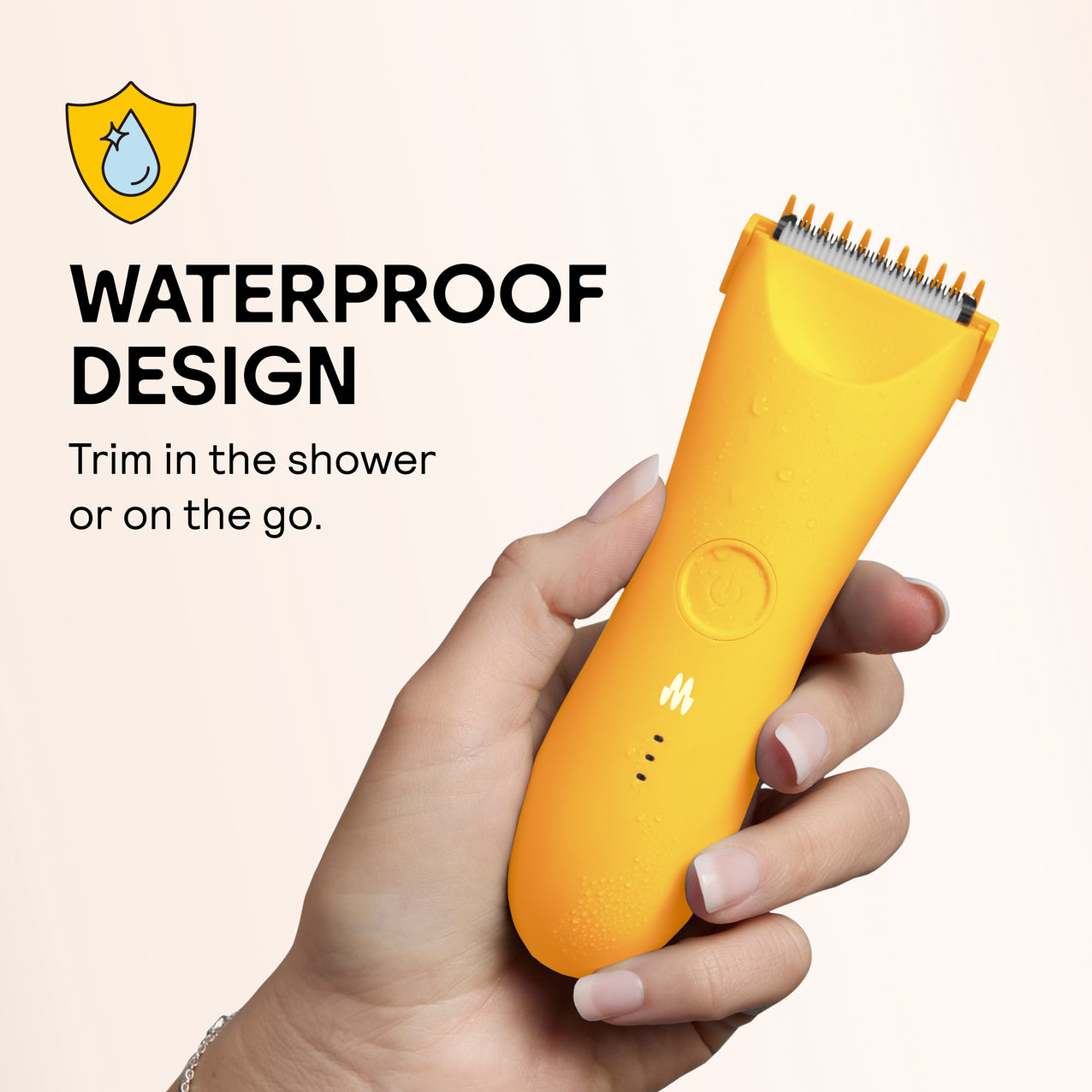 Yellow waterproof electric hair trimmer with water drops held in hand, ideal for shower or travel grooming.