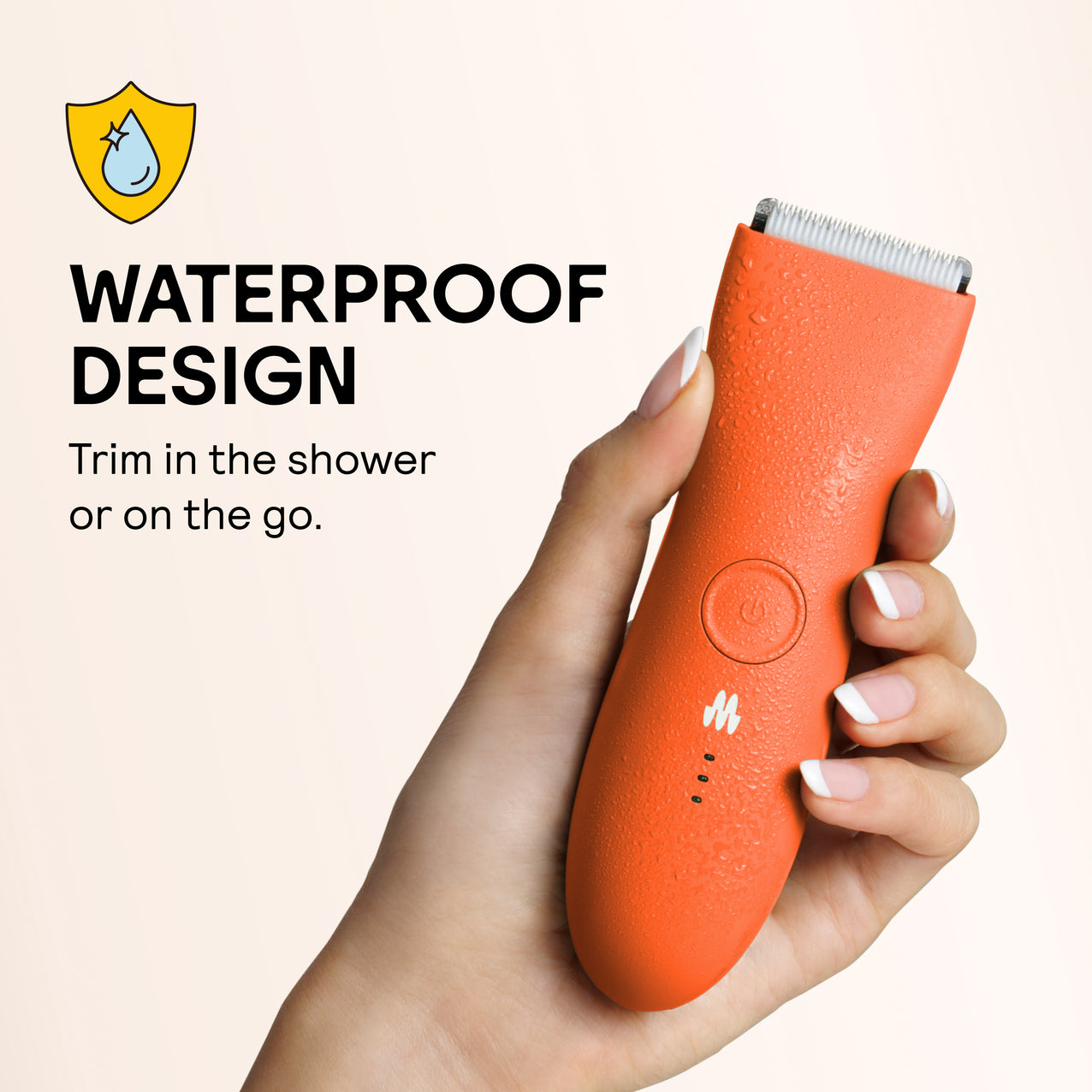 Hand holding waterproof orange electric shaver with water droplets, designed for trimming in shower or on the go.