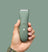 Green cordless electric hair trimmer with power button and LED indicators held in hand, grooming tool for men.