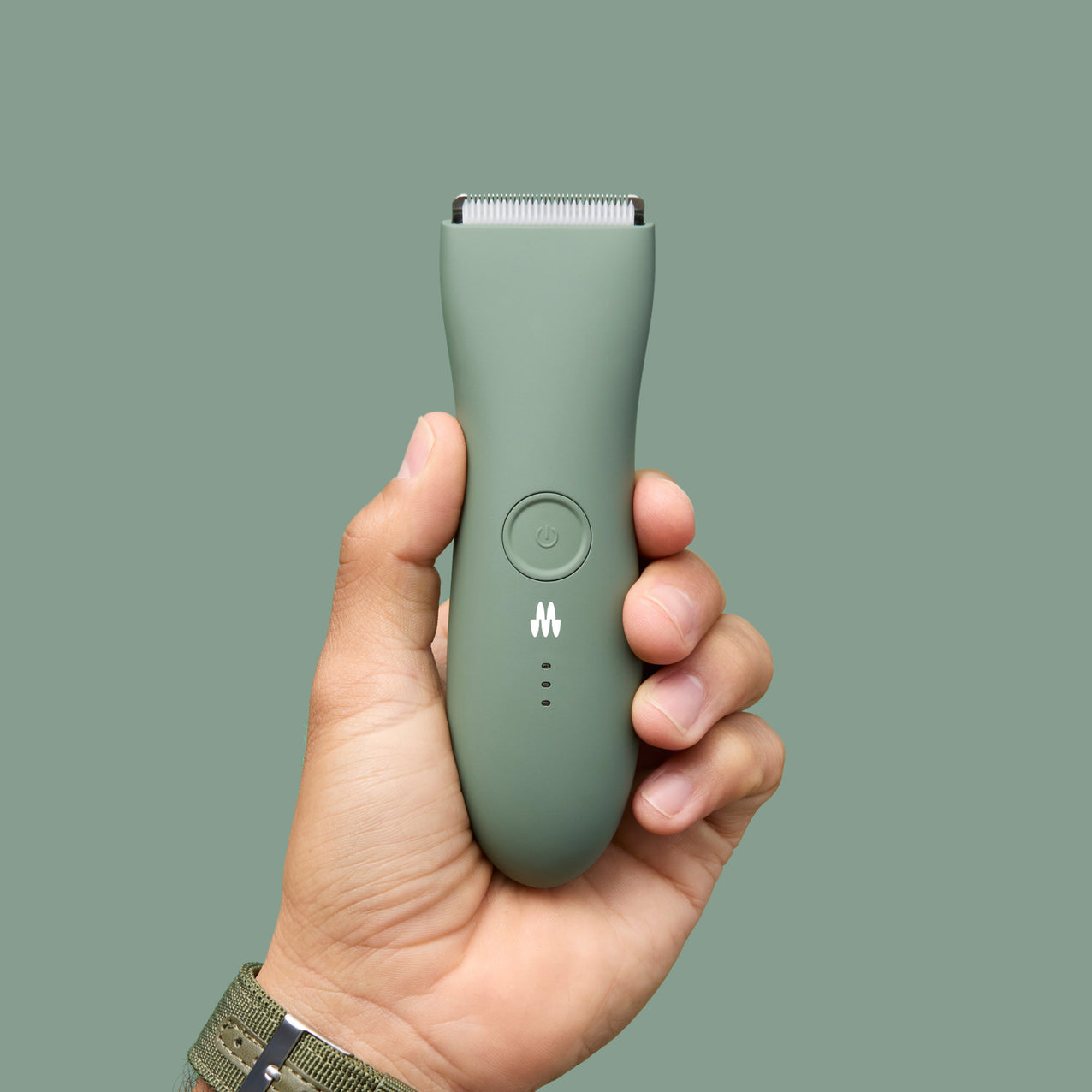 Green cordless electric hair trimmer with power button and LED indicators held in hand, grooming tool for men.