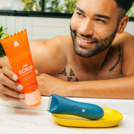 Man holding The Scrub exfoliator by Meridian Grooming next to an MEridian electric trimmer